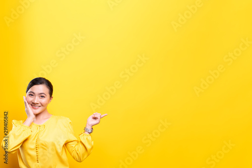Woman pointing to copy space isolated over yellow background