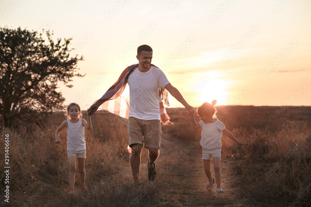 Fototapeta premium A happy family with an American flag at sunset.