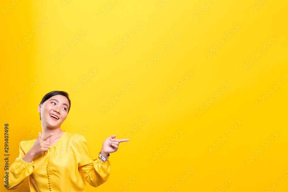 Woman pointing to copy space isolated over yellow background Woman pointing to copy space isolated over yellow background