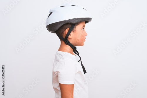 Beautiful kid boy wearing bike security helmet standing over isolated white background looking to side, relax profile pose with natural face with confident smile.
