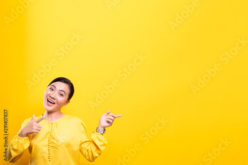 Woman pointing to copy space isolated over yellow background