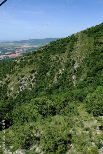 Mountain peaks covered with greenery and blue sky.