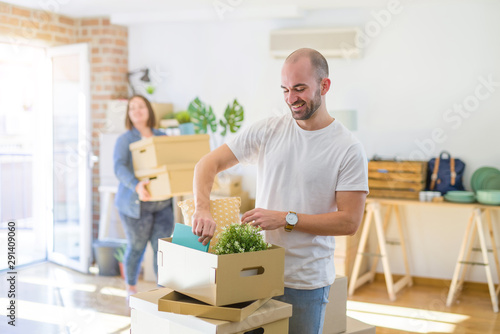Young couple moving to new apartment, handsome man moving cardboard boxes and smiling happy