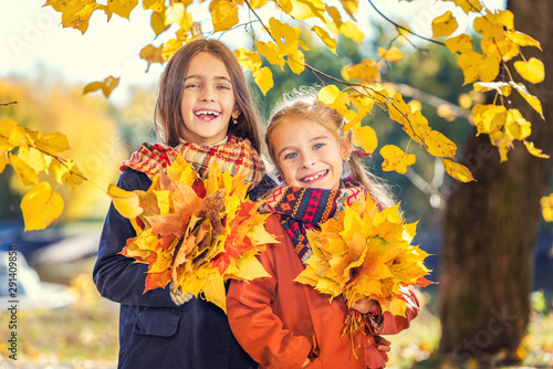 Two cute smiling 8 years old girls posing together in a park on a sunny autumn day. Friendship concept. © sborisov