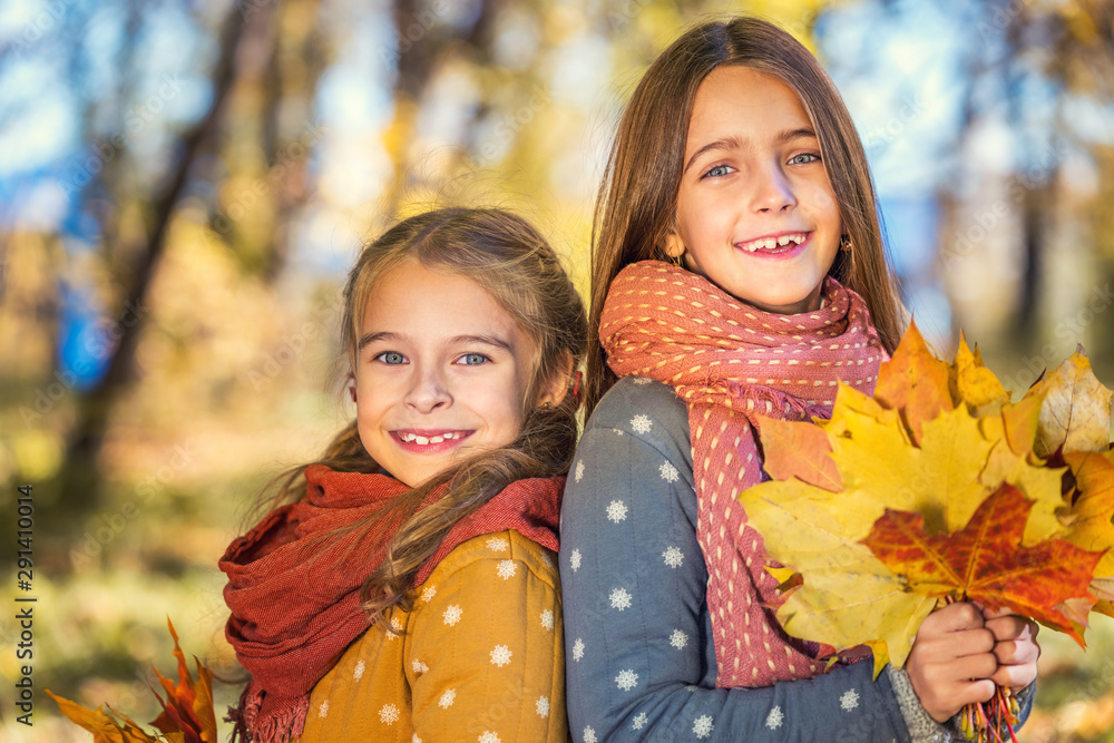 Two cute smiling 8 years old girls posing together in a park on a sunny autumn day. Friendship concept. Two cute smiling 8 years old girls posing together in a park on a sunny autumn day. Friendship concept.