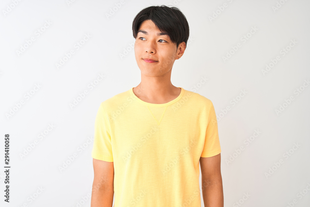 Obraz premium Chinese man wearing yellow casual t-shirt standing over isolated white background smiling looking to the side and staring away thinking.