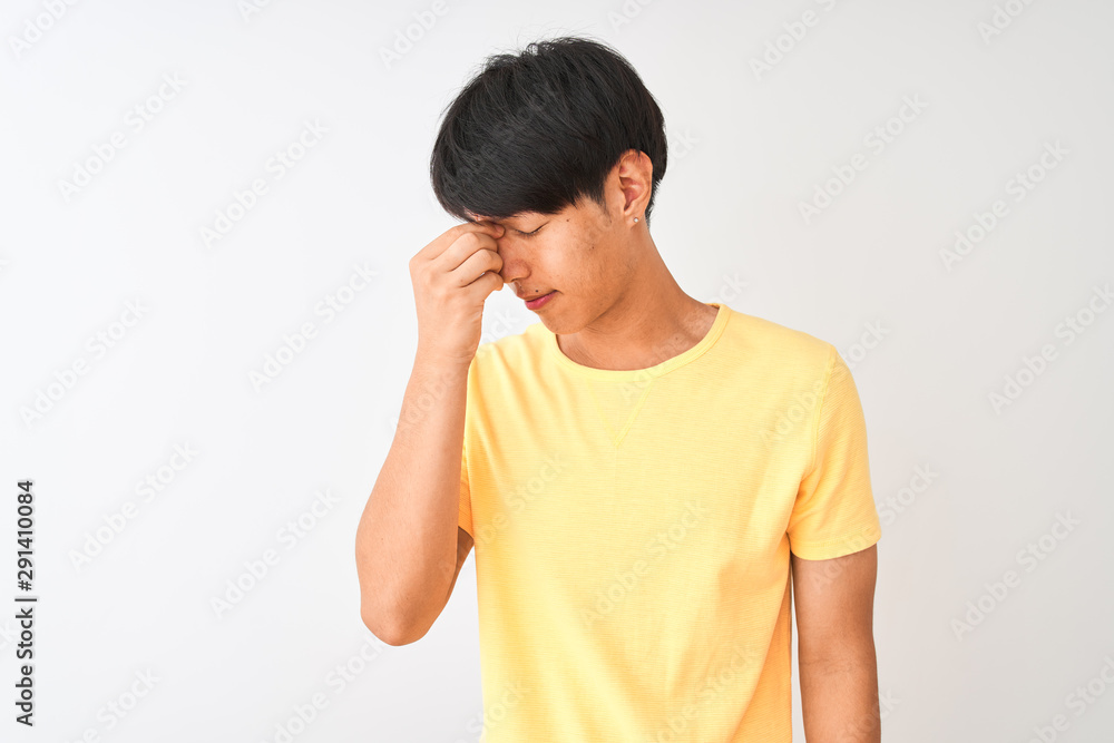 Chinese man wearing yellow casual t-shirt standing over isolated white background tired rubbing nose and eyes feeling fatigue and headache. Stress and frustration concept. Chinese man wearing yellow casual t-shirt standing over isolated white background tired rubbing nose and eyes feeling fatigue and headache. Stress and frustration concept.