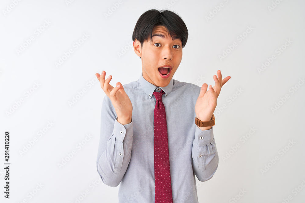 Chinese businessman wearing elegant tie standing over isolated white background celebrating crazy and amazed for success with arms raised and open eyes screaming excited. Winner concept Chinese businessman wearing elegant tie standing over isolated white background celebrating crazy and amazed for success with arms raised and open eyes screaming excited. Winner concept