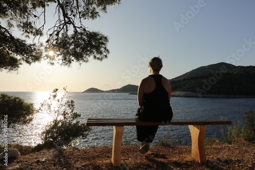 woman sitting alone on a bench, enjoying the tranquil sea scape and just relax