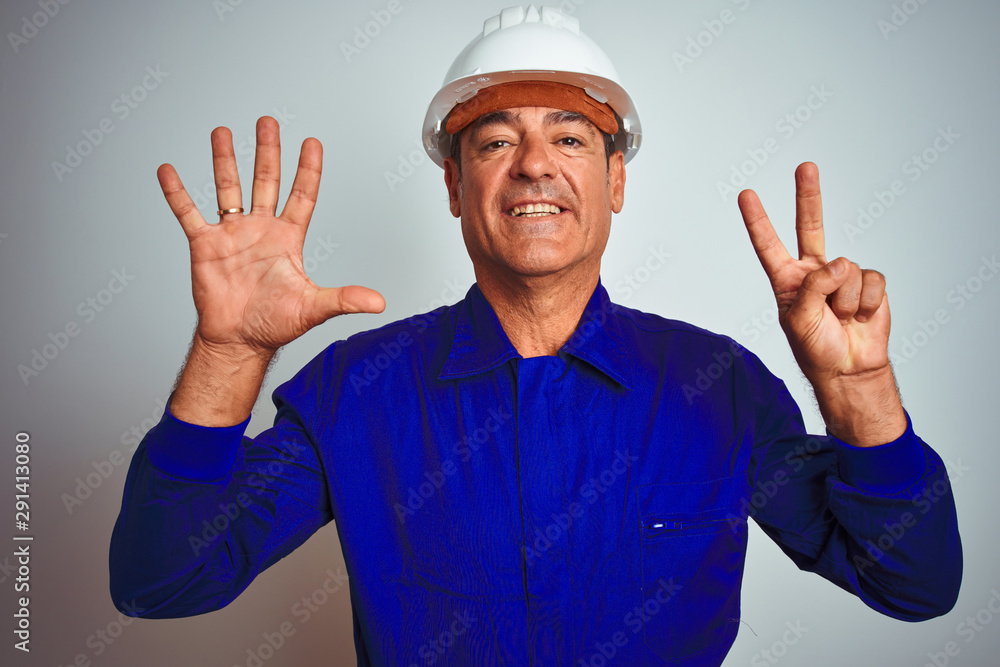 Handsome middle age worker man wearing uniform and helmet over isolated white background showing and pointing up with fingers number seven while smiling confident and happy. Handsome middle age worker man wearing uniform and helmet over isolated white background showing and pointing up with fingers number seven while smiling confident and happy.