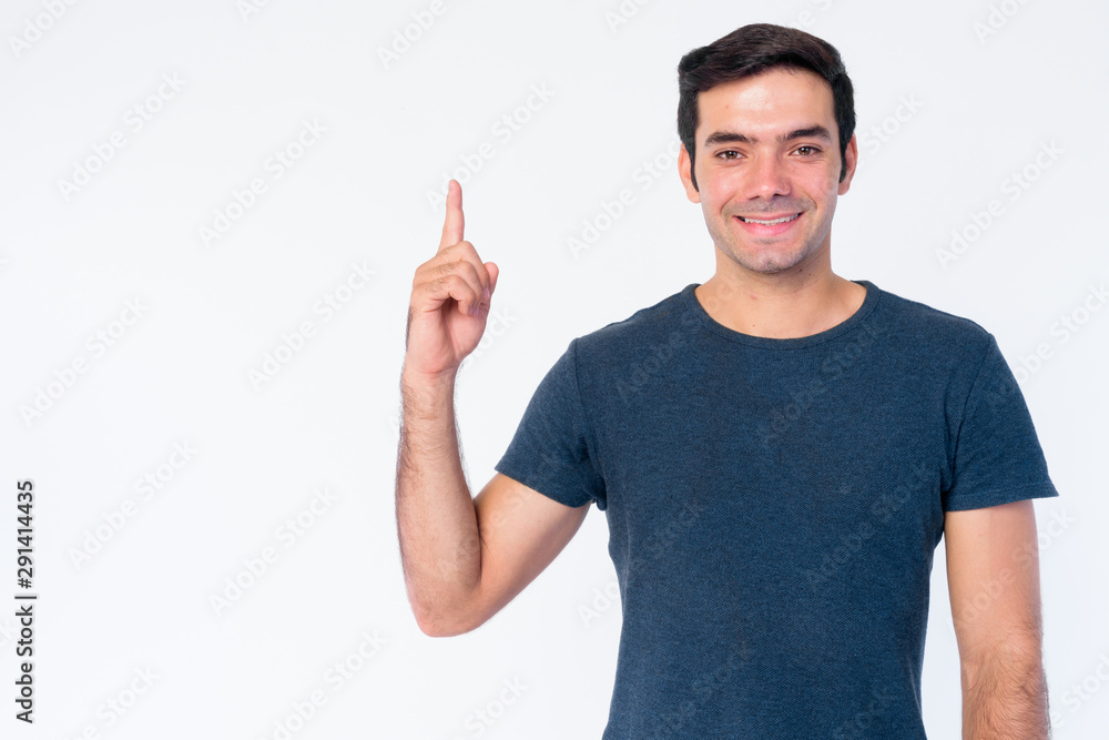 Portrait of happy young handsome Persian man pointing up Portrait of happy young handsome Persian man pointing up