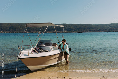 young man dragging a boat up on to the beach. man pulls a boat ashore to moor it to the shore. © producer