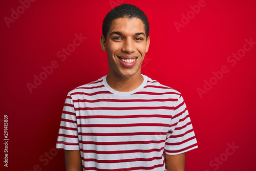 Young handsome arab man wearing striped t-shirt over isolated red background with a happy and cool smile on face. Lucky person.