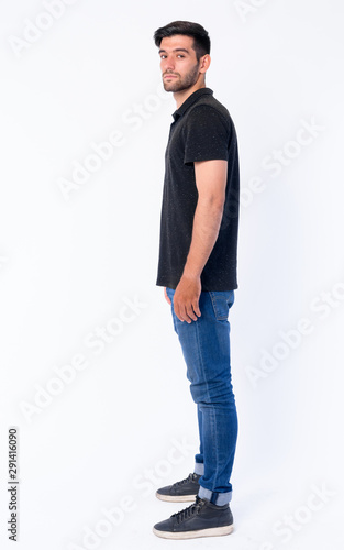 Full body shot profile view of young bearded Persian man looking at camera