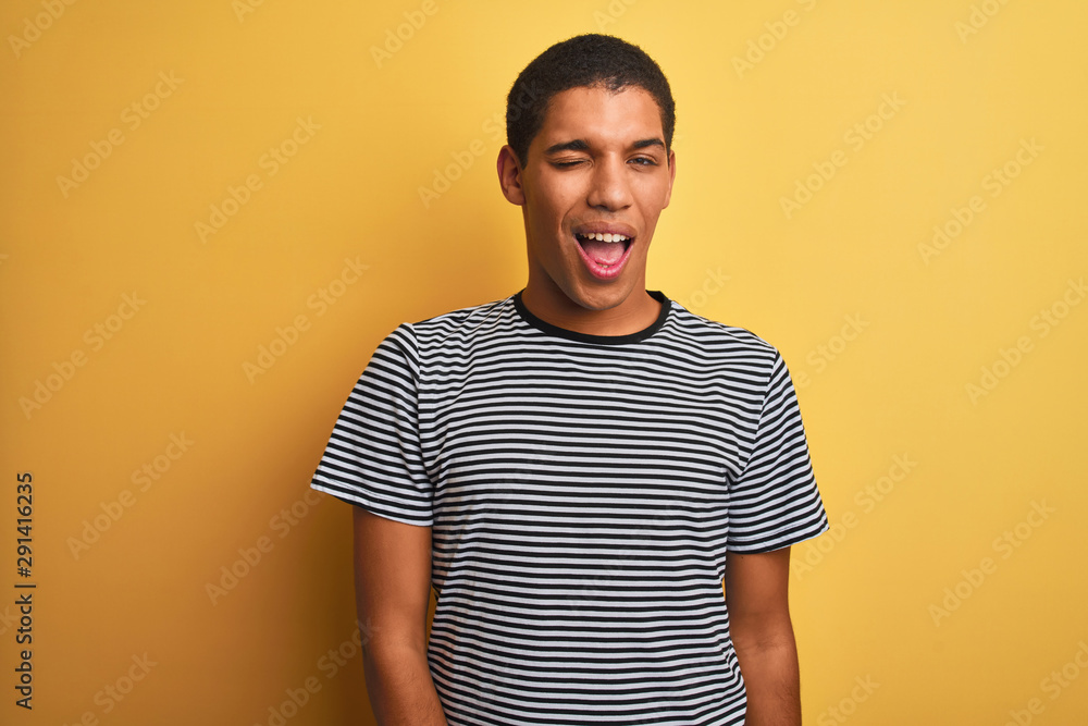 Young handsome arab man wearing navy striped t-shirt over isolated yellow background winking looking at the camera with sexy expression, cheerful and happy face. Young handsome arab man wearing navy striped t-shirt over isolated yellow background winking looking at the camera with sexy expression, cheerful and happy face.