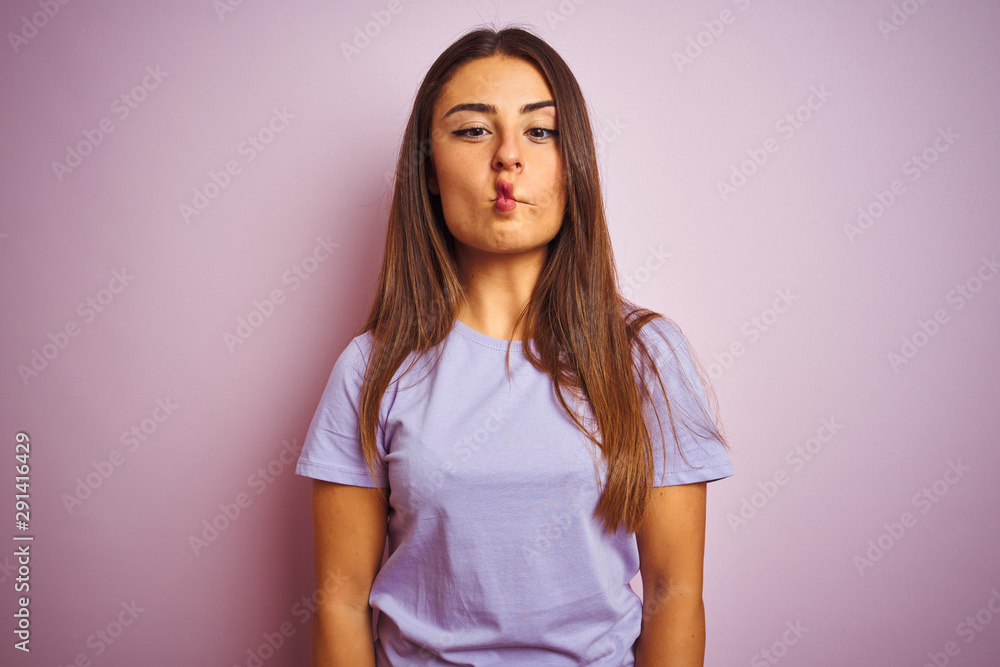 Young beautiful woman wearing casual t-shirt standing over isolated pink background making fish face with lips, crazy and comical gesture. Funny expression. Young beautiful woman wearing casual t-shirt standing over isolated pink background making fish face with lips, crazy and comical gesture. Funny expression.