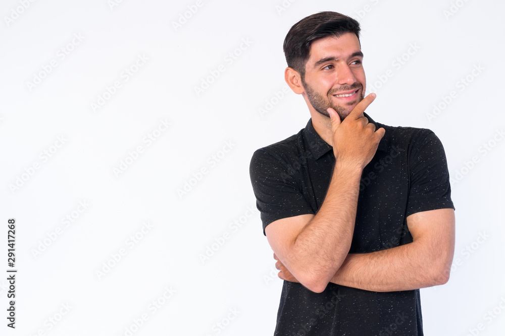 Portrait of happy young bearded Persian man thinking and looking up Portrait of happy young bearded Persian man thinking and looking up