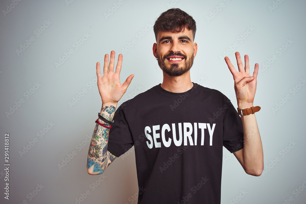 Young safeguard man with tattoo wering security uniform over isolated white background showing and pointing up with fingers number nine while smiling confident and happy. Young safeguard man with tattoo wering security uniform over isolated white background showing and pointing up with fingers number nine while smiling confident and happy.