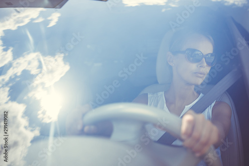 Fotografie, Obraz Young female driver driving her car unedr scorching Sun on a hot summer day (col