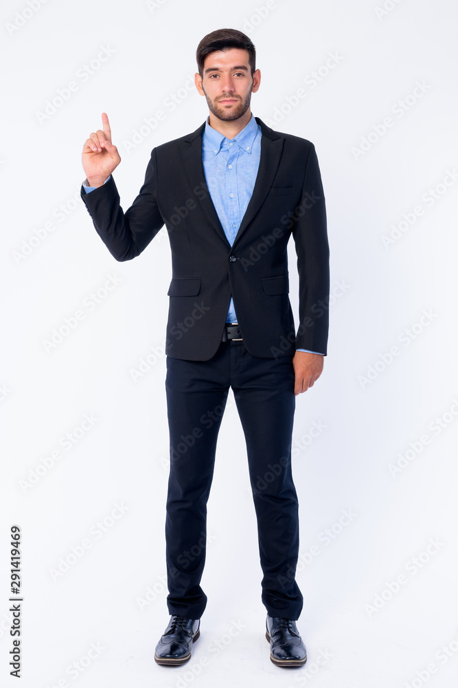 Full body shot of young bearded Persian businessman pointing up