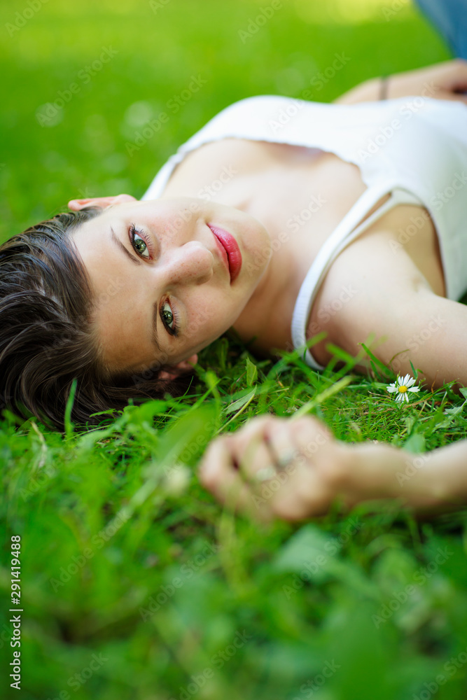 Close-up portrait of an attractive young woman outdoors, lying in the grass. Close-up portrait of an attractive young woman outdoors, lying in the grass.