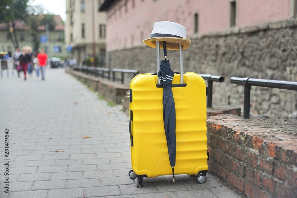 Travel tourism concept, yellow plastic suitcase, hat, umbrella