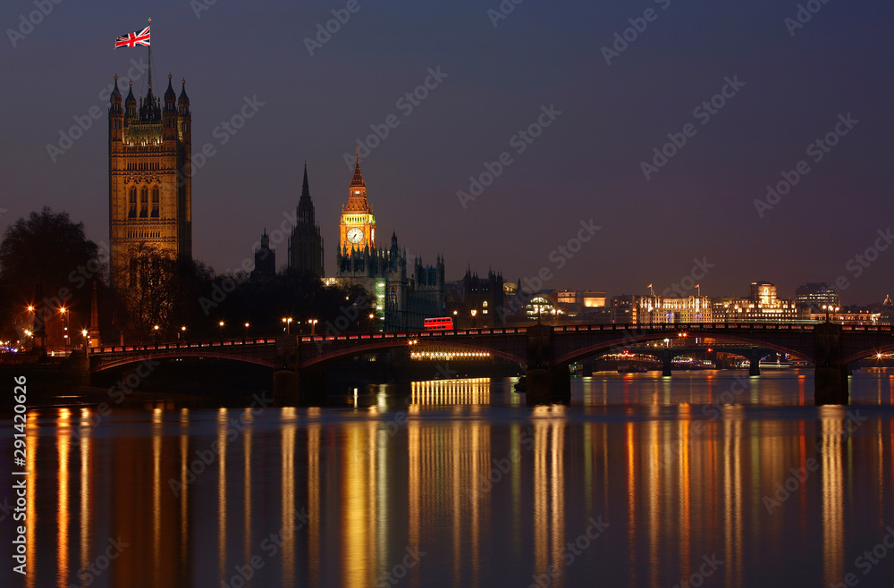 Night view of Westminster Palace over illuminated Thames River.