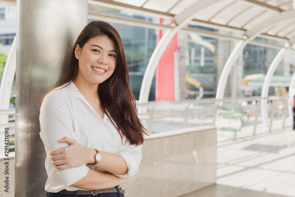 Confident Asian woman in white shirt cross her arm on modern footbridge.