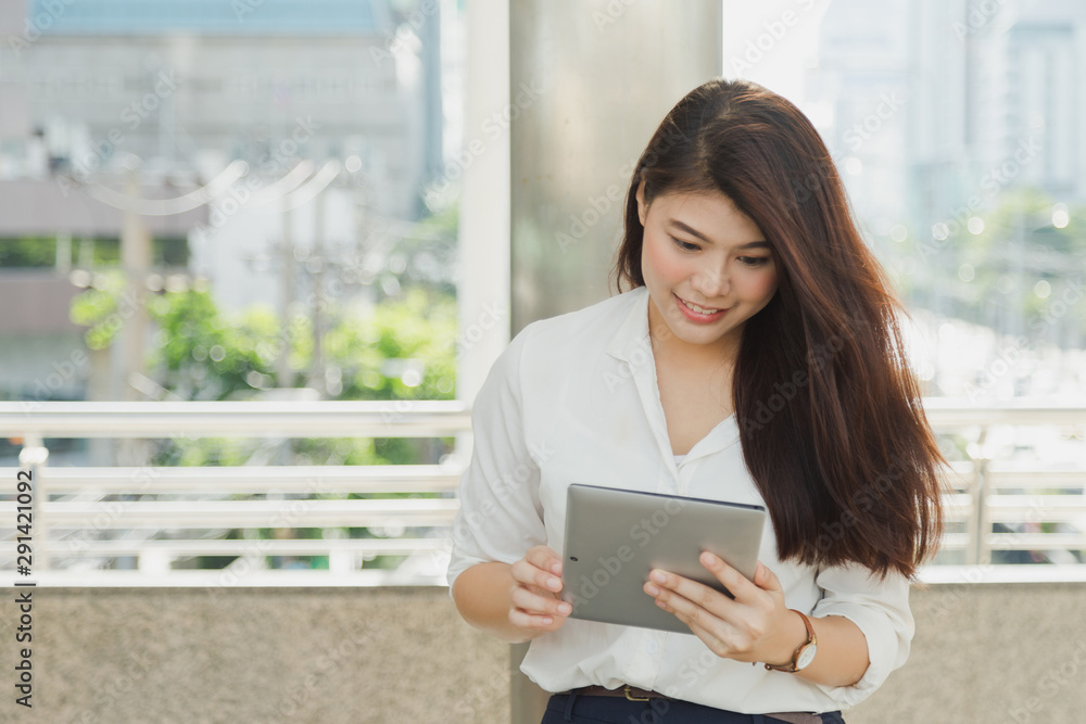 Smart Asian woman watching her tablet on modern footbridge. Smart Asian woman watching her tablet on modern footbridge.