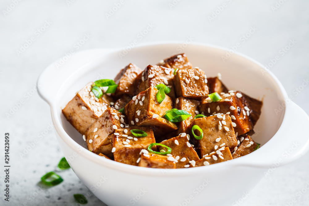 Teriyaki tofu with sesame seeds and green onion in white bowl. Vegan food concept. Teriyaki tofu with sesame seeds and green onion in white bowl. Vegan food concept.