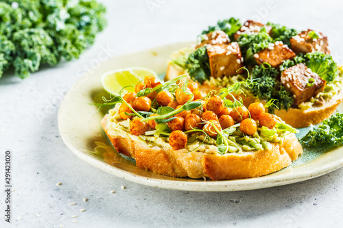 Vegan open sandwiches with guacamole, tofu, chickpeas and sprouts on a plate.