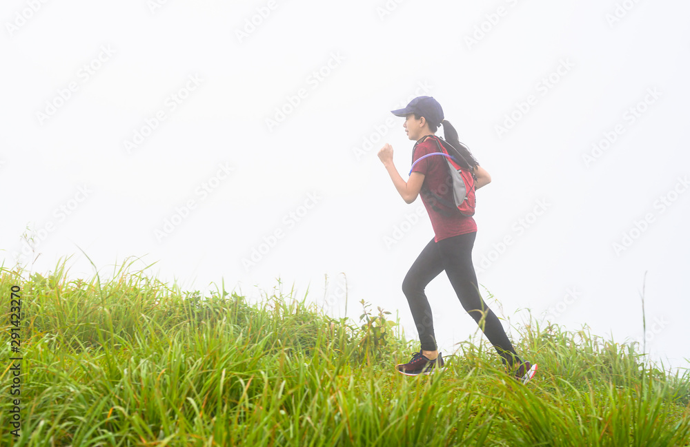 sporty woman running trail competition upon the hill mountain in the morning, with mist are full around the meadow area of the hil sporty woman running trail competition upon the hill mountain in the morning, with mist are full around the meadow area of the hil