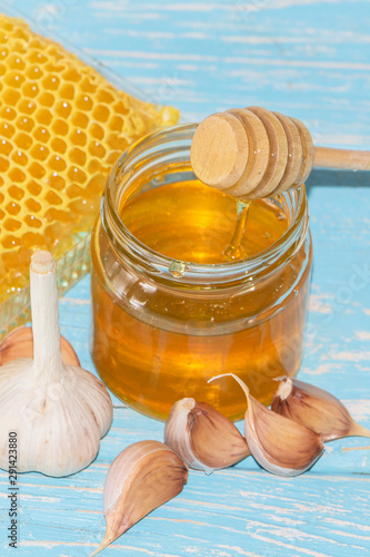 Honey and pieces of garlic on the background of honeycomb. Honey in a glass jar and honeycomb. photo