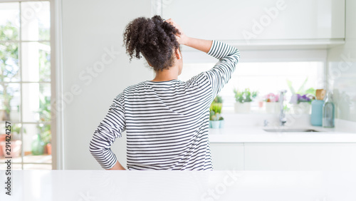 Beautiful african american woman with afro hair wearing casual striped sweater Backwards thinking about doubt with hand on head