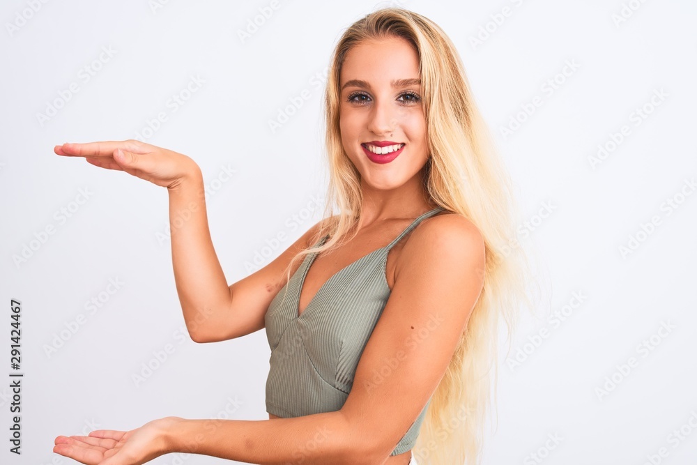 Young beautiful woman wearing casual green t-shirt standing over isolated white background gesturing with hands showing big and large size sign, measure symbol. Smiling looking at the camera Young beautiful woman wearing casual green t-shirt standing over isolated white background gesturing with hands showing big and large size sign, measure symbol. Smiling looking at the camera