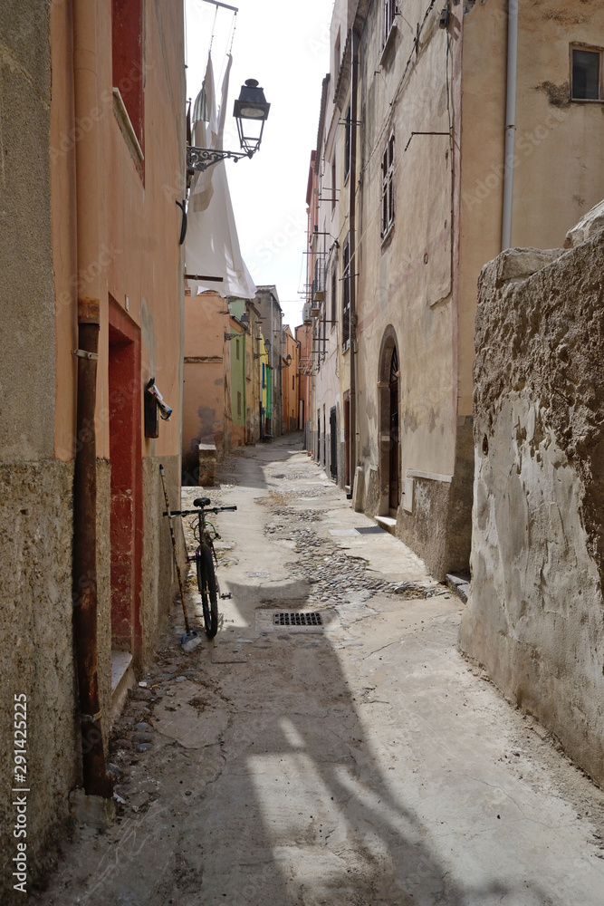 typical narrow street of the ancient village of Bosa in northern Sardinia. A bicycle leaning against the wall of a house in the foreground