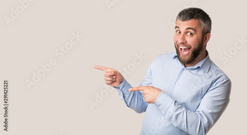Excited man pointing with two fingers aside at empty space