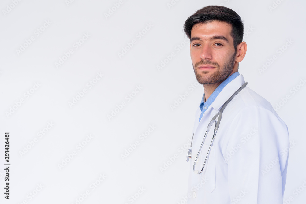 Profile view of young bearded Persian man doctor looking at camera Profile view of young bearded Persian man doctor looking at camera