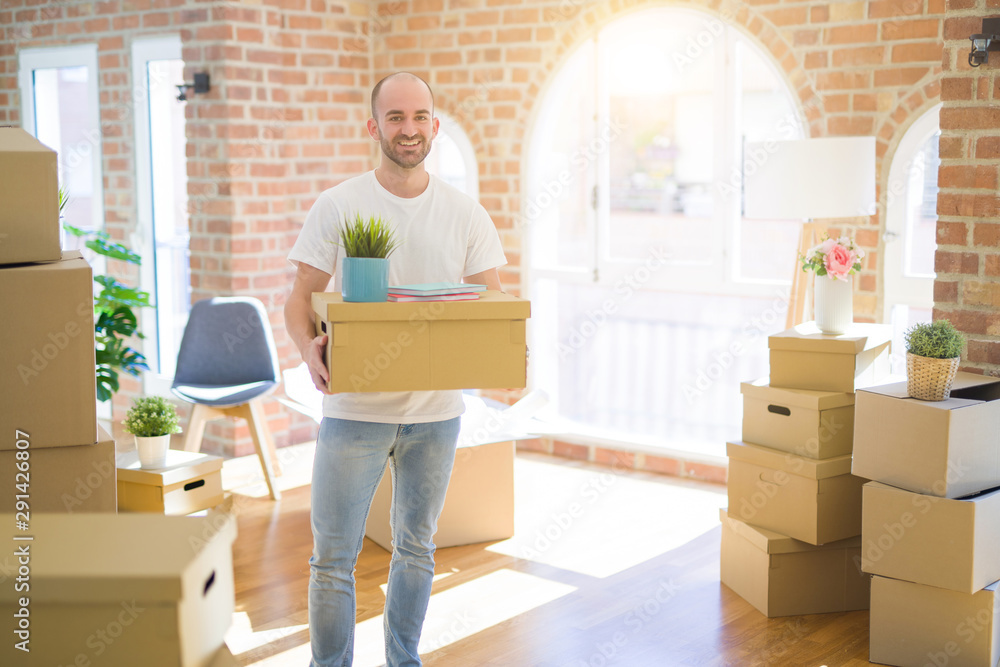 Young handsome man moving to a new house, holding cardboxes smiling very happy for new apartment Young handsome man moving to a new house, holding cardboxes smiling very happy for new apartment