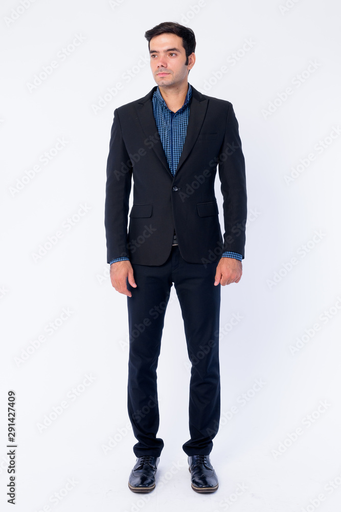 Full body shot of young handsome Persian businessman in suit thinking Full body shot of young handsome Persian businessman in suit thinking