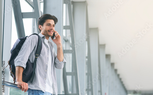 Young man traveller talking on mobile phone in airport