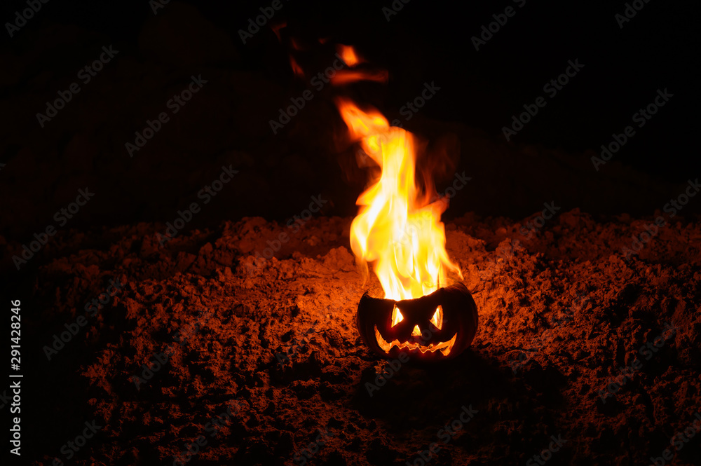 Tongues of flame in a pumpkin. jack-o-lantern on fire on a black background. Halloween symbol on the ground. Trick or treat. Close up. Tongues of flame in a pumpkin. jack-o-lantern on fire on a black background. Halloween symbol on the ground. Trick or treat. Close up.
