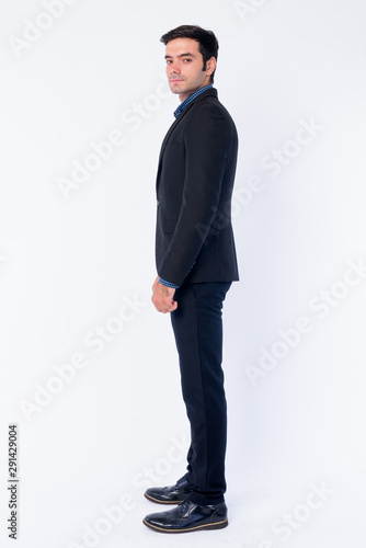Full body shot profile view of young Persian businessman looking at camera