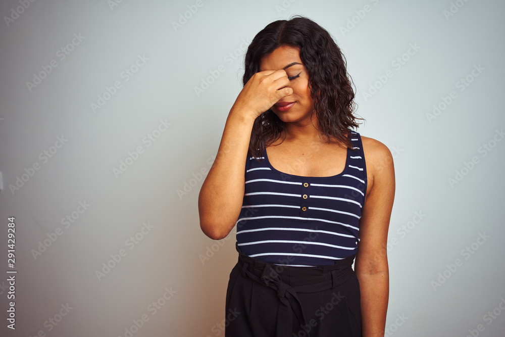 Transsexual transgender woman wearing striped t-shirt over isolated white background tired rubbing nose and eyes feeling fatigue and headache. Stress and frustration concept. Transsexual transgender woman wearing striped t-shirt over isolated white background tired rubbing nose and eyes feeling fatigue and headache. Stress and frustration concept.