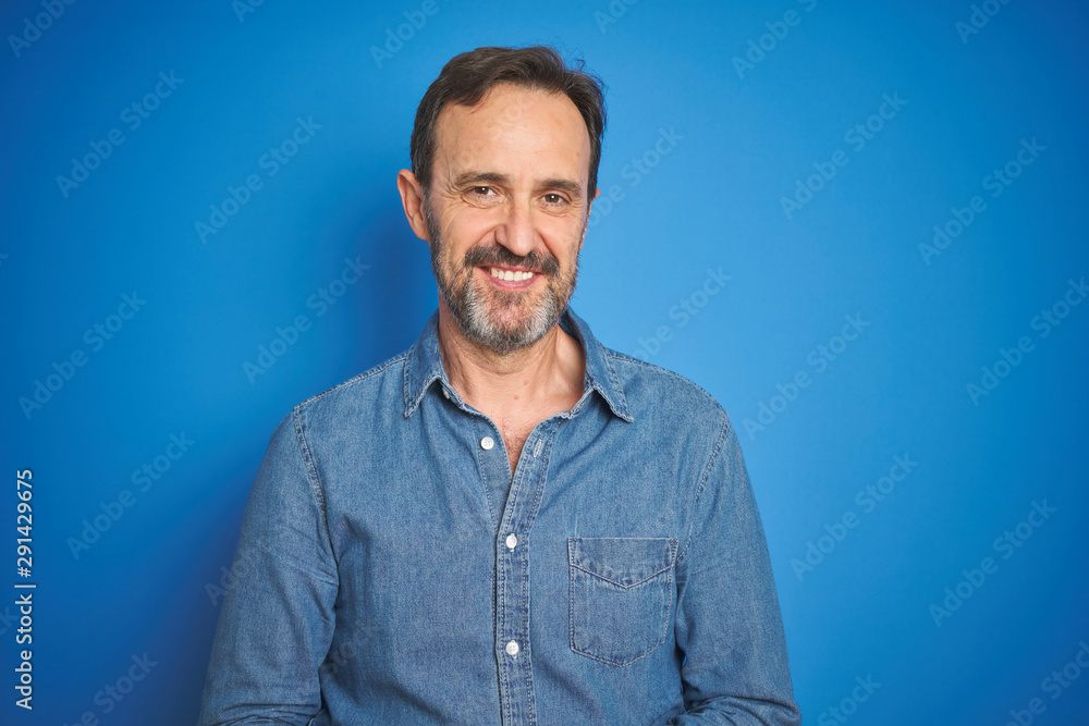 Obraz premium Handsome middle age senior man with grey hair over isolated blue background with hands together and crossed fingers smiling relaxed and cheerful. Success and optimistic