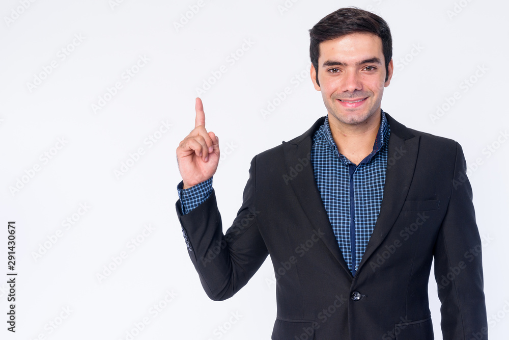 Portrait of happy young handsome Persian businessman in suit pointing up Portrait of happy young handsome Persian businessman in suit pointing up