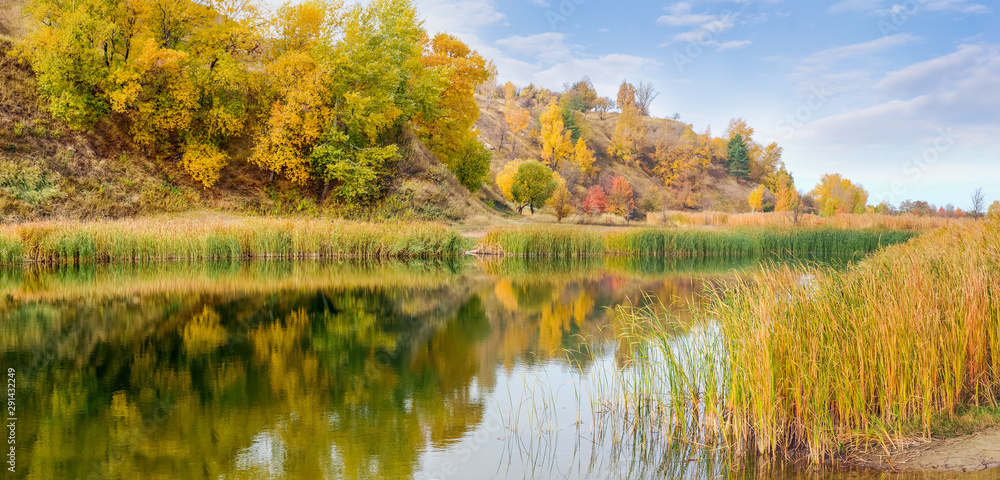 Scenic lake at the foot of hill in autumn, panoramic view