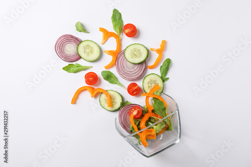 Glass bowl with fresh vegetables slices on white background, copy space