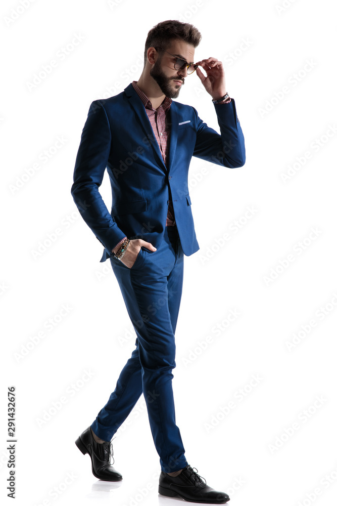 formal businessman walking with hand in pocket fixing glasses formal businessman walking with hand in pocket fixing glasses