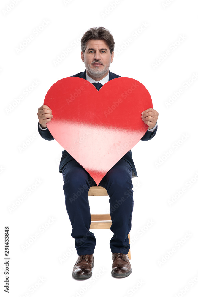 businessman sitting and holding a big red heart businessman sitting and holding a big red heart